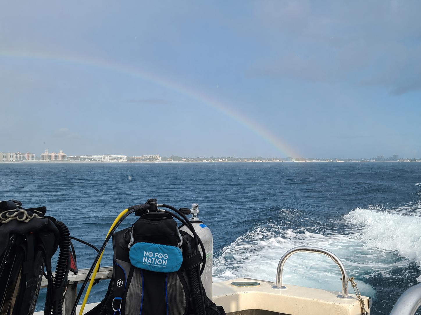 No Fog Nation mask cover on a dive tank with a rainbow over the ocean from the boat